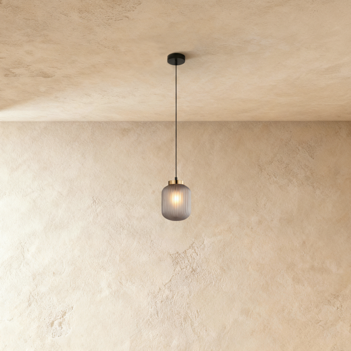Vahni pendant light by Residence Supply hanging against a plain grey background, showcasing its modern design and sleek shape.