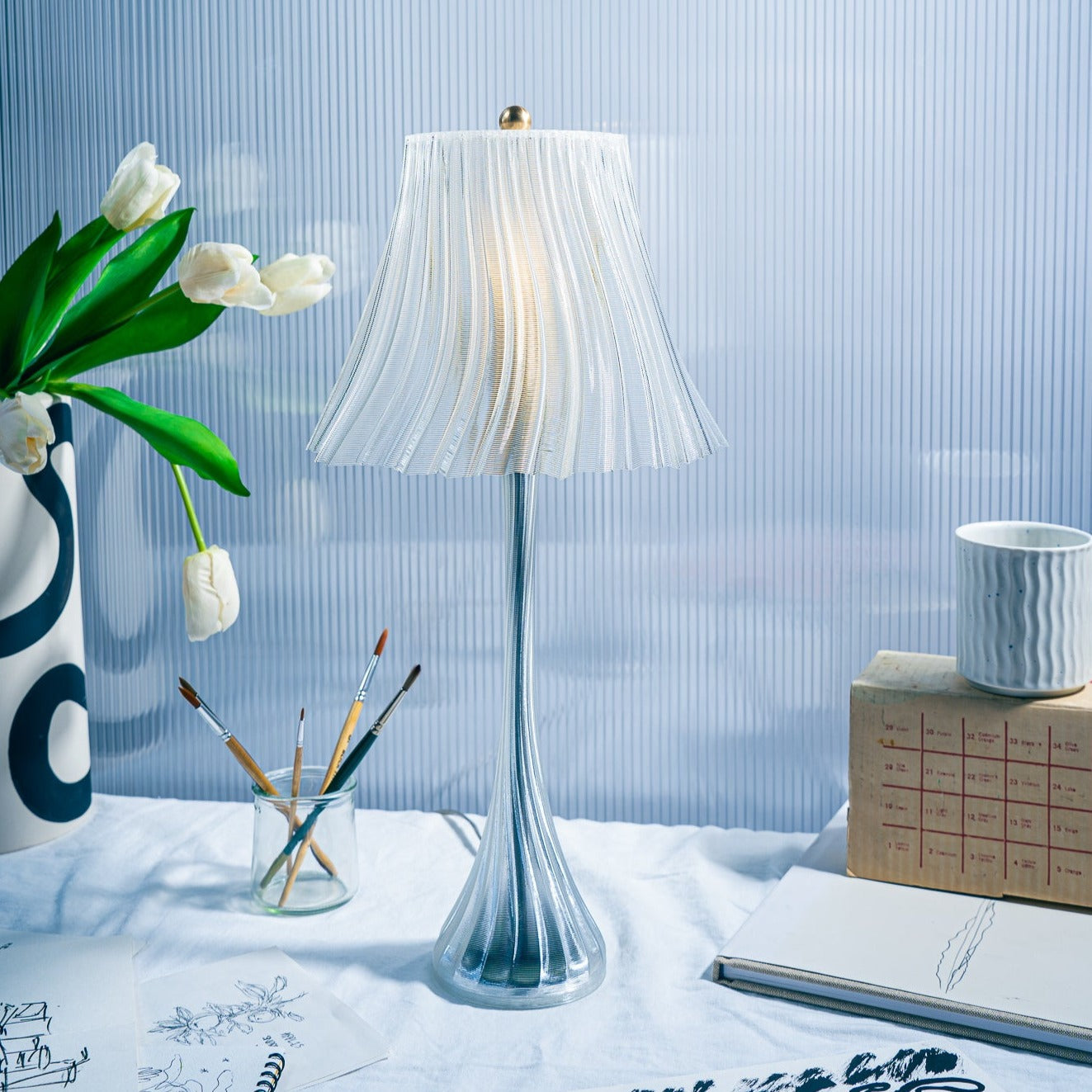 Wooj Design Pleat Lamp with pleated fabric shade, modern table lamp style, featuring a sleek base and soft ambient lighting.