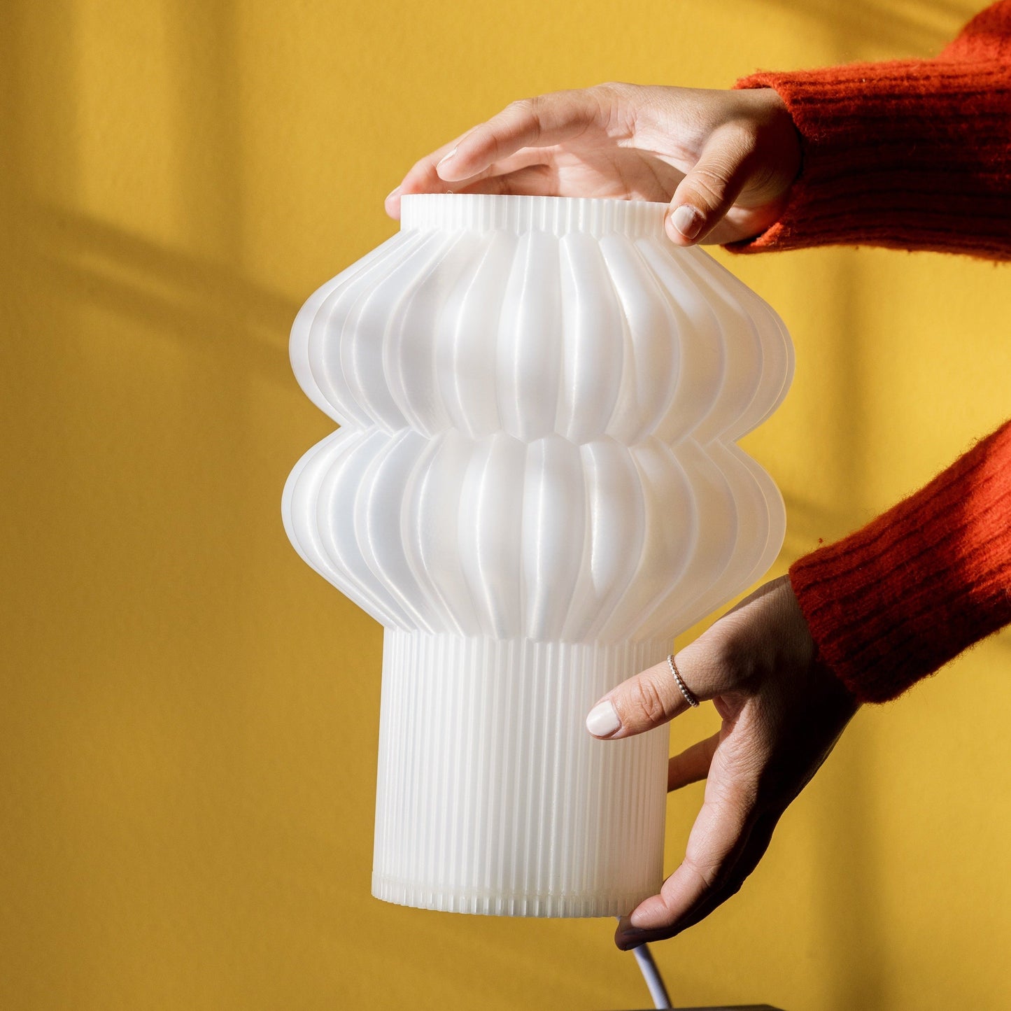 Terra Labs Oppi table lamp with a modern design, featuring a sleek base and a soft glowing lampshade on a wooden surface.