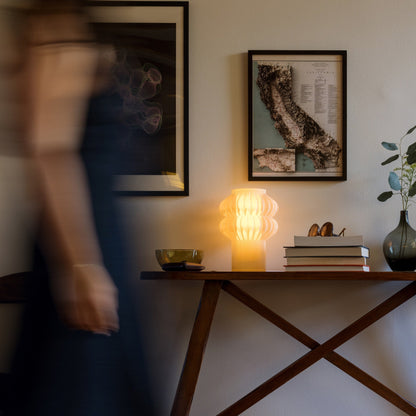 Terrra Labs Oppi table lamp with a sleek, modern design featuring a cylindrical shade and minimalist base on a wooden surface.
