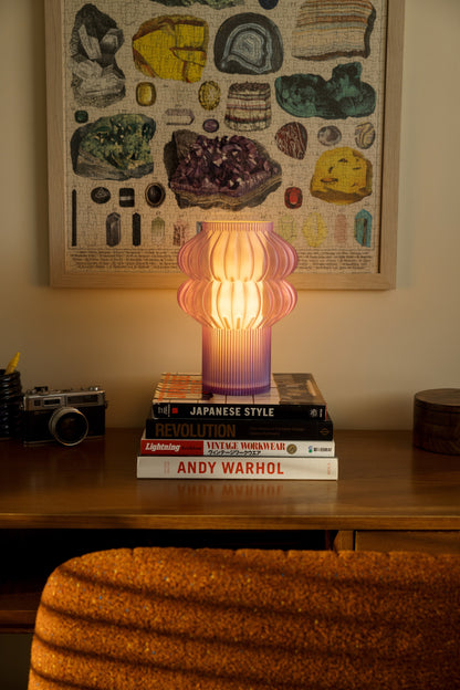 Terra Labs Oppi table lamp with a sleek, modern design and warm light, placed on a wooden side table.