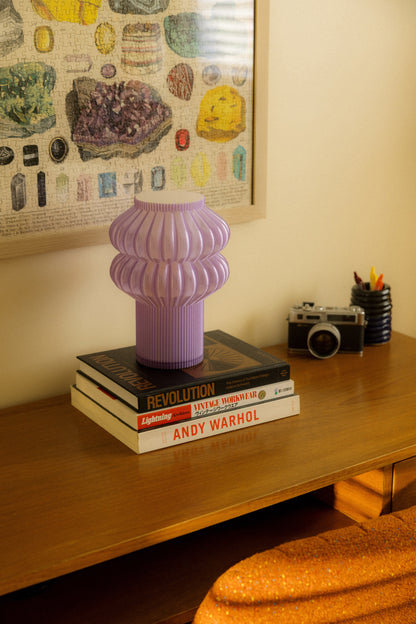 Terra Labs Oppi table lamp with a modern design, featuring a sleek base and a soft glowing fabric shade on a wooden surface.