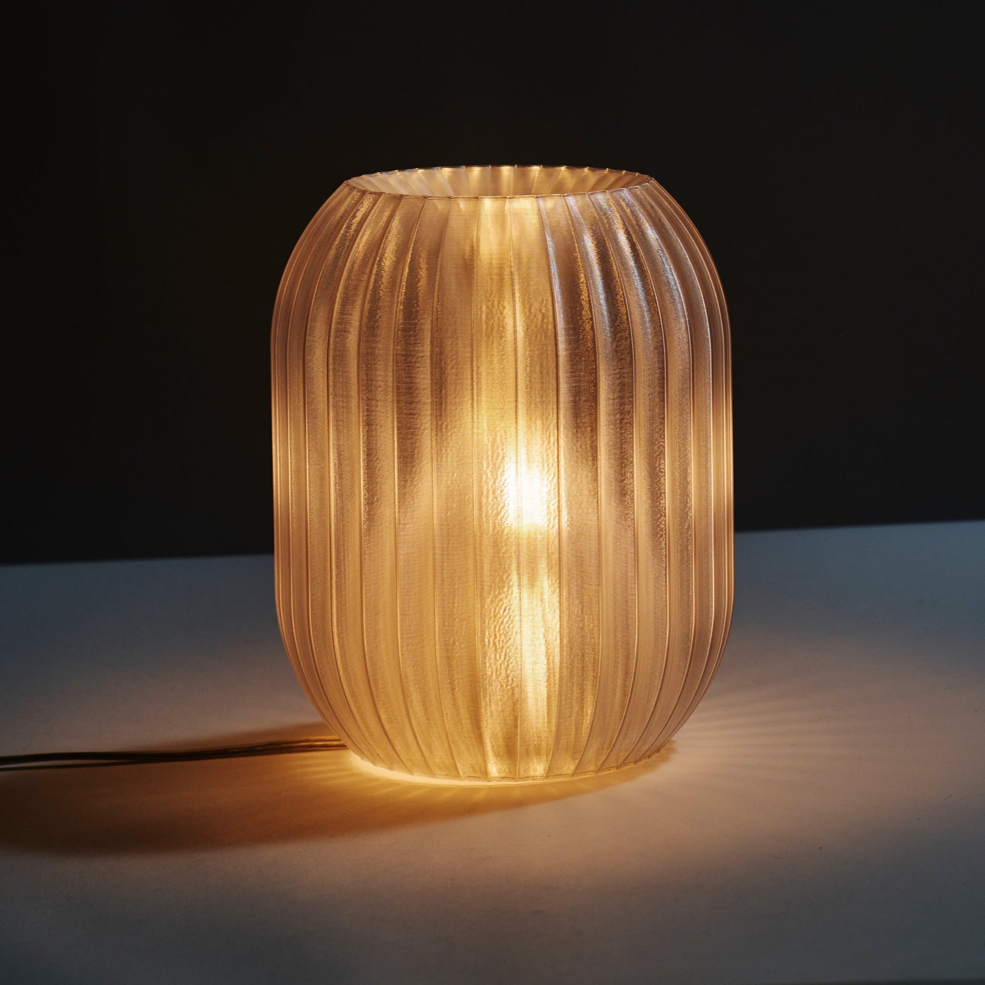 Wooj Design Allium Lamp with clear glass shade and floral-inspired design, displayed on a wooden surface in a modern interior setting.