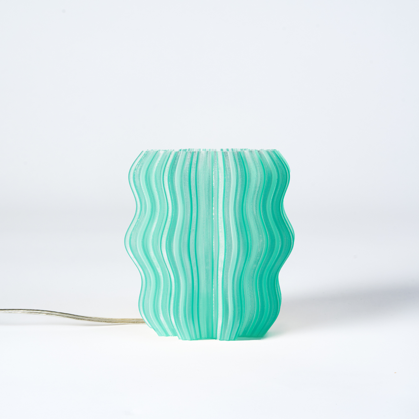 Mini Wavy Lamp by Wooj Design, green and beige color, modern wavy shape, illuminated on a white background.
