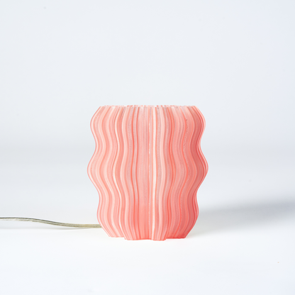 Mini Wavy Lamp by Wooj Design featuring a sleek, wavy-shaped orange lamp with a modern aesthetic and smooth finish.