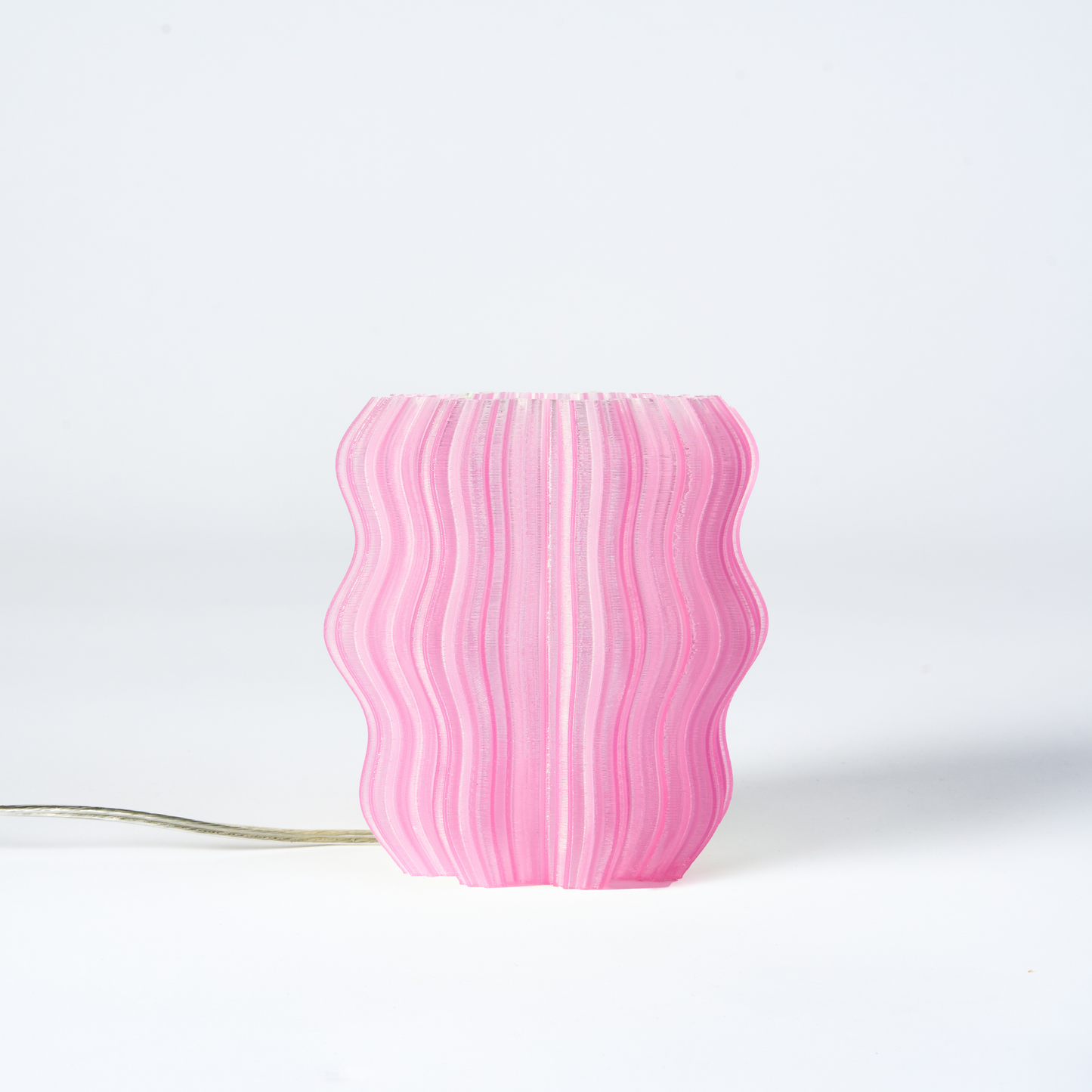 Mini Wavy Lamp by Wooj Design, featuring a sleek wavy shape and soft lighting in pastel pink, perfect for modern decor.
