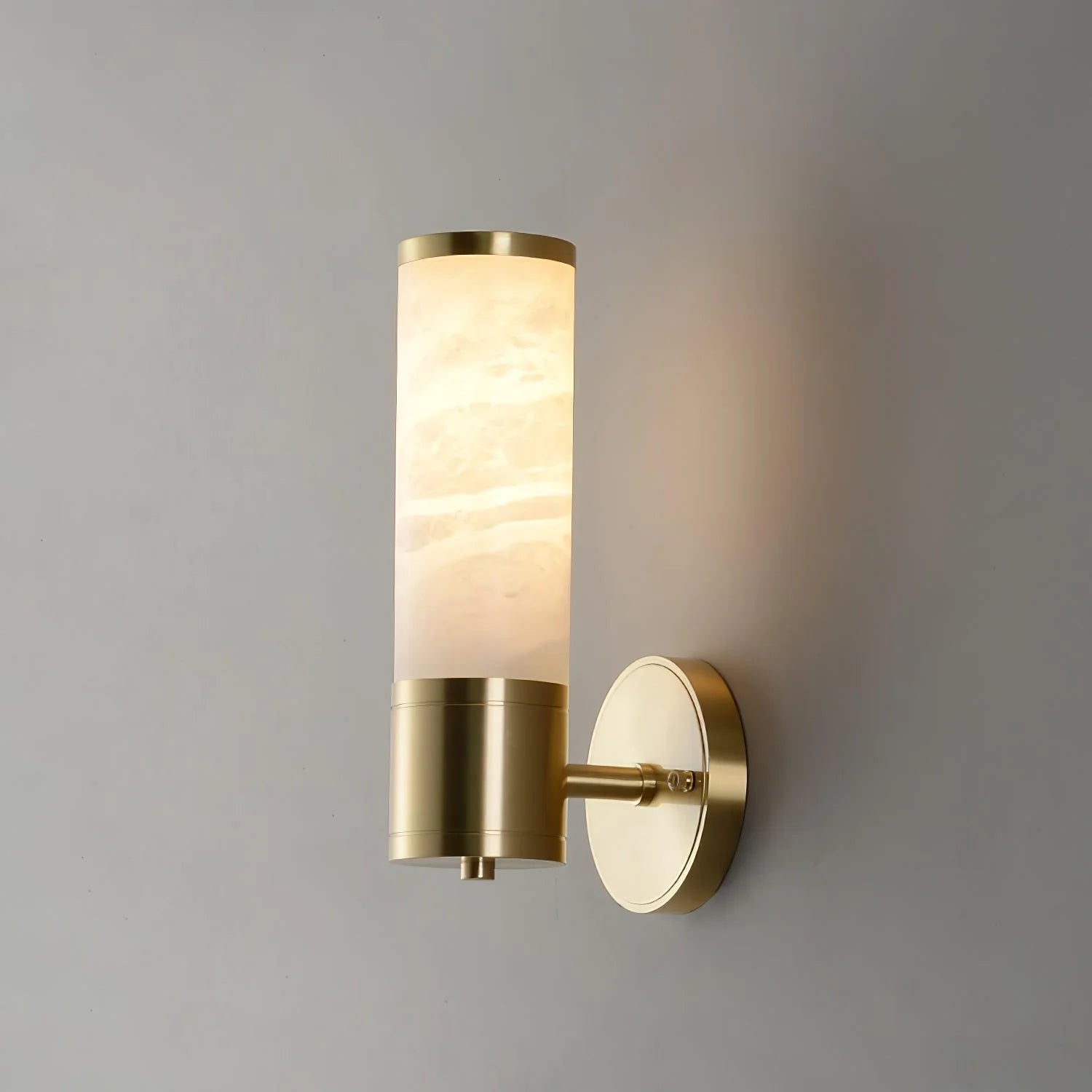 Alabaster Lampatron cylindrical wall lamp by korewolamp hanging on a wall, showcasing its smooth alabaster finish and modern design.