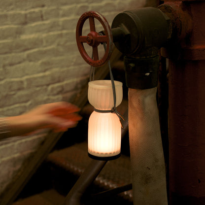 Wooj Design cordless camp lantern illuminating a campsite with a warm glow, ideal for outdoor camping and portable lighting.