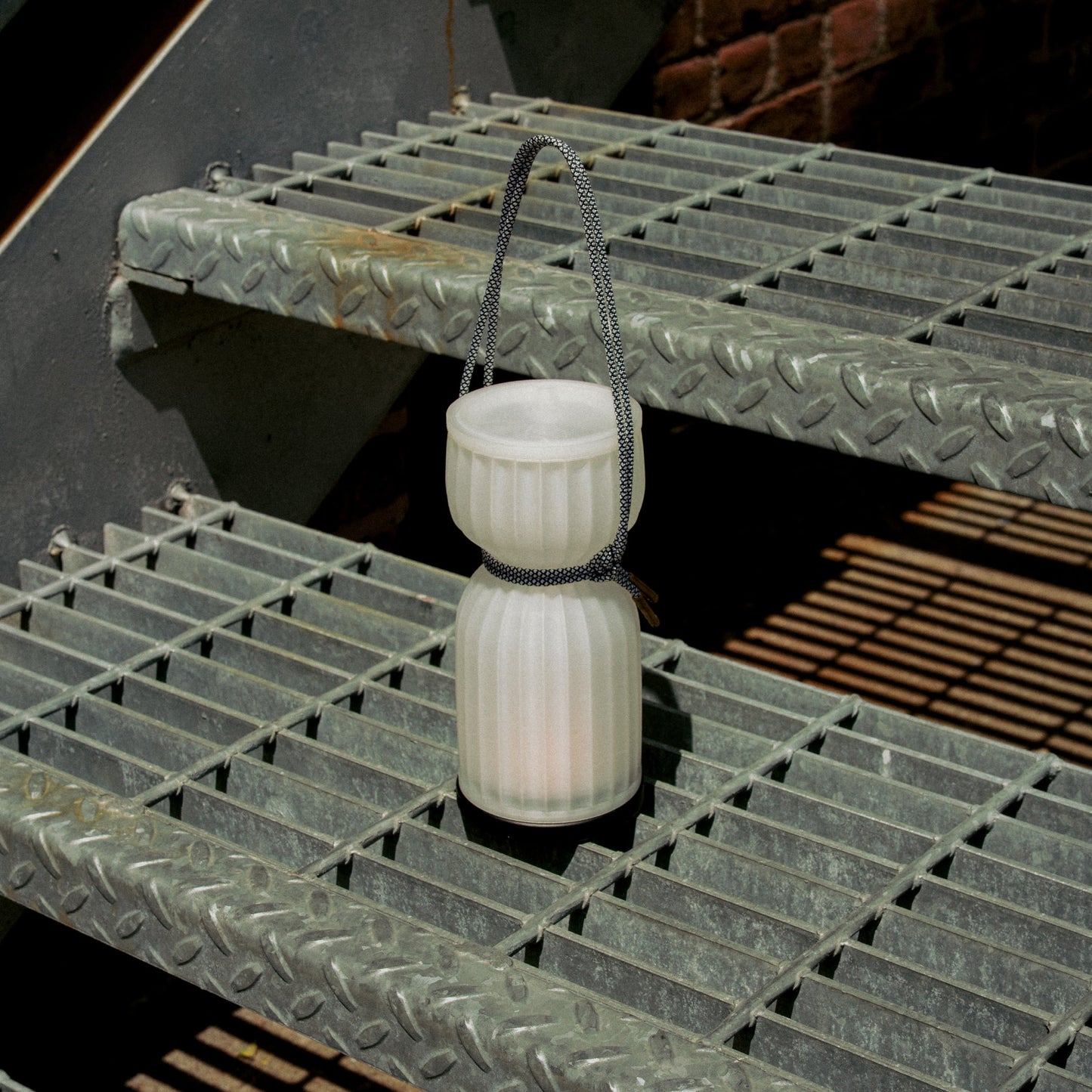 Wooj Design cordless camp lantern illuminating a campsite at night with a warm, bright glow in a outdoor setting.