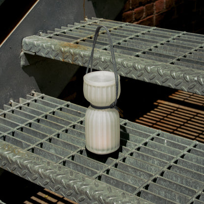 Wooj Design cordless camp lantern illuminating a campsite at night with a warm, bright glow in a outdoor setting.