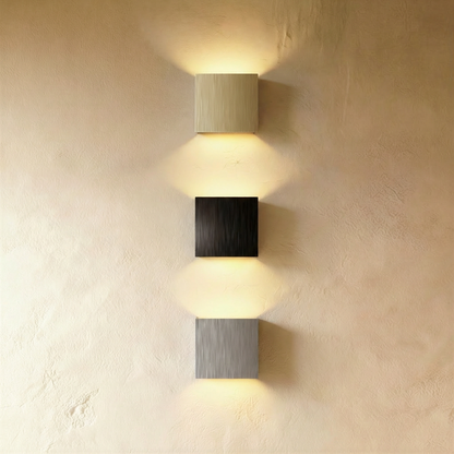 Brushed metal Lior Wall Lamp by Residence Supply with sleek, modern design mounted on a wall for ambient lighting.