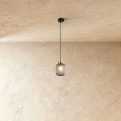 Vahni pendant light by Residence Supply hanging against a plain grey background, showcasing its modern design and sleek shape.