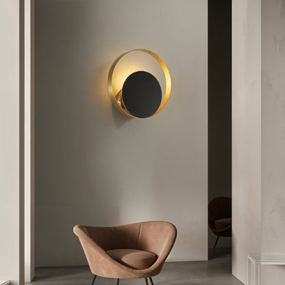 Residence Supply Eclipse Wall Lamp mounted on a wall, featuring a modern, circular design with a sleek black finish.