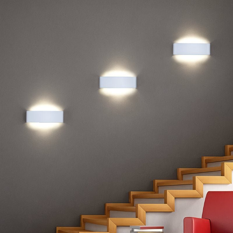 Femi Wall Lamp by Residence Supply mounted on a wall with a sleek, modern design and soft ambient lighting.