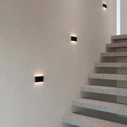 Femi wall lamp by Residence Supply mounted on a wall with a sleek modern design and warm ambient lighting.