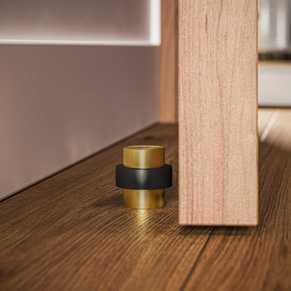 Residence Supply Finio door stop mounted on baseboard, durable metal door hardware for preventing door damage.