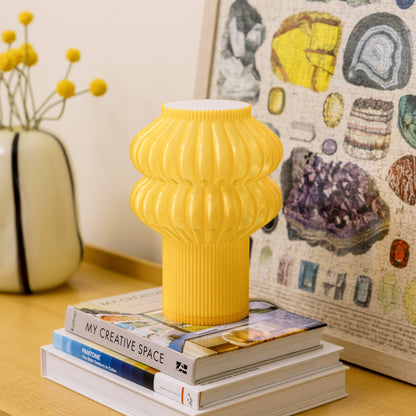 Terra Labs Oppi Table Lamp with honey-colored ceramic base and white fabric shade on a wooden table.