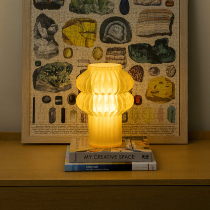 Terra Labs Oppi Table Lamp with honey-colored ceramic base and white fabric shade on a wooden surface.