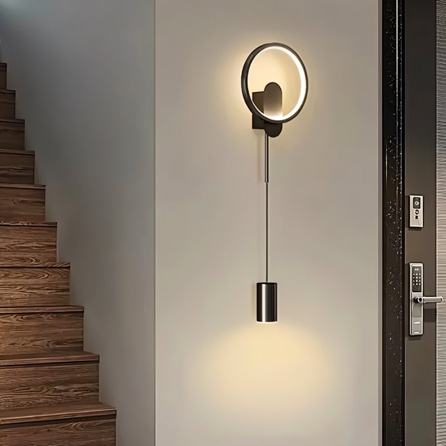 Black Imrat Wall Lamp by Residence Supply mounted on a staircase wall, providing stylish and functional lighting.