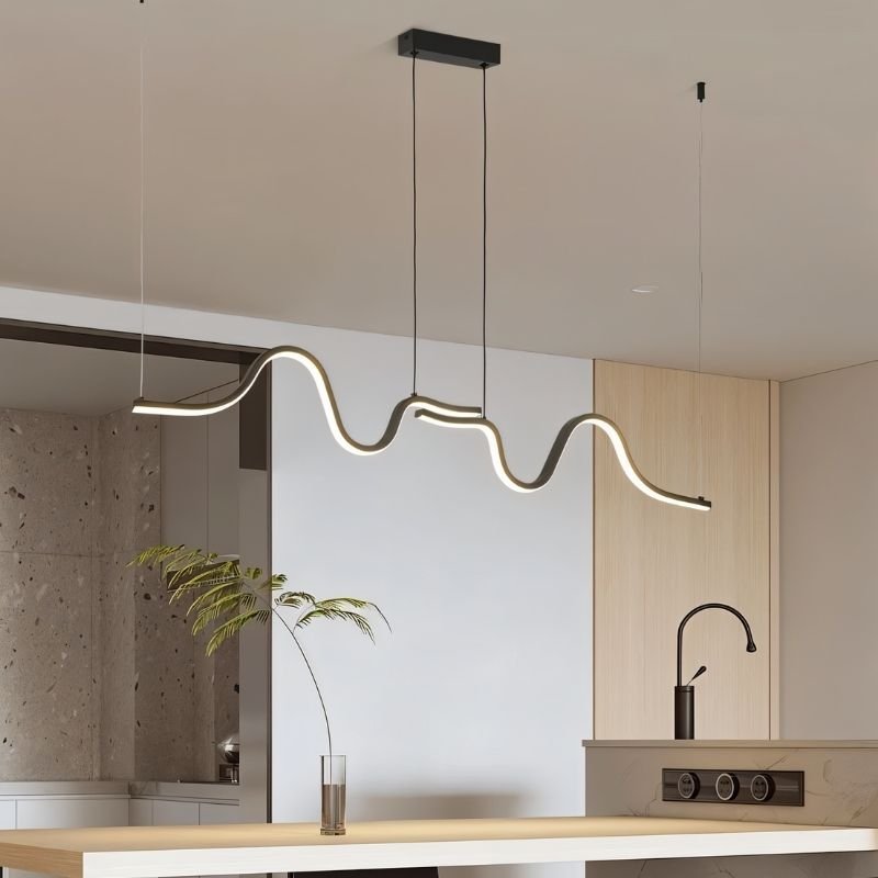 Lissar Wave Pendant Light by Residence Supply hanging above a kitchen counter, featuring a sleek, modern design with a wave-shaped shade.