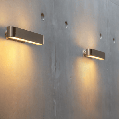 Modern Munira Wall Lamp by Residence Supply with sleek metal finish and warm lighting, mounted on a stylish wall.