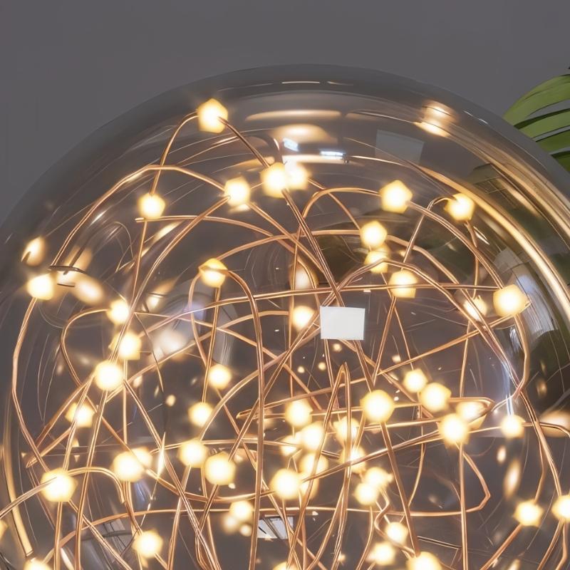 Close-up of the Naxlyn Ceiling Light by Residence Supply featuring a glass sphere design with soft illumination.