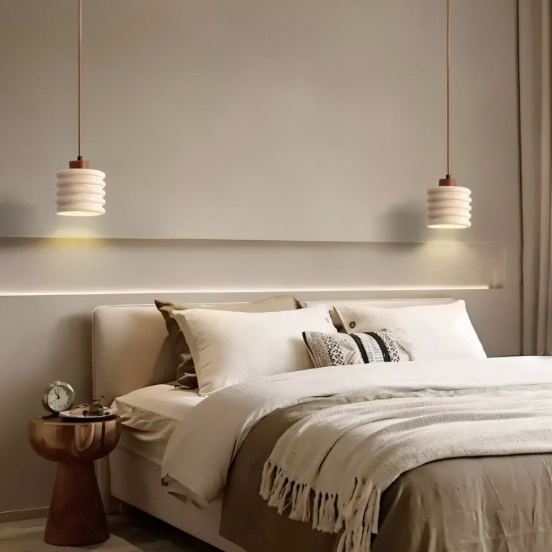 Nexon pendant light by Residence Supply hanging in a bedroom with a travertine finish, providing stylish ambient lighting.