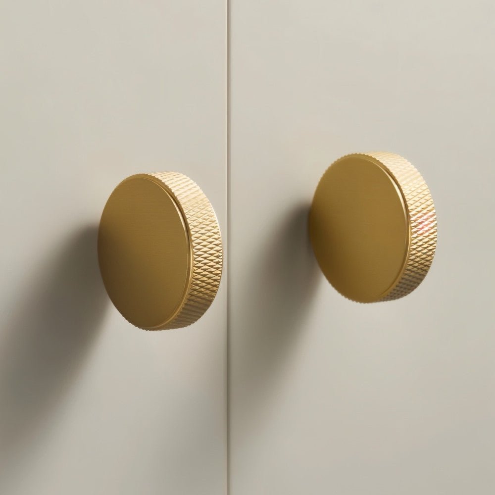 Cylindrical knurled Noah cabinet knob in matte black, made of metal, mounted on a wooden cabinet for modern kitchen decor.