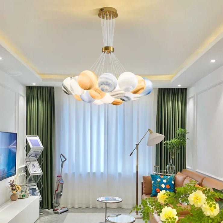 Orbea chandelier with multiple glass globes and brass accents, hanging from a ceiling fixture in a modern interior setting.