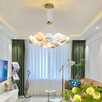 Orbea chandelier with multiple glass globes and brass accents, hanging from a ceiling fixture in a modern interior setting.