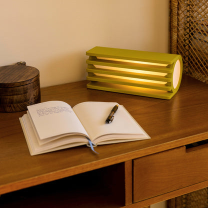 Terra Labs radiator table lamp with mustard-colored finish, modern design, and sleek cylindrical shape on a wooden surface.