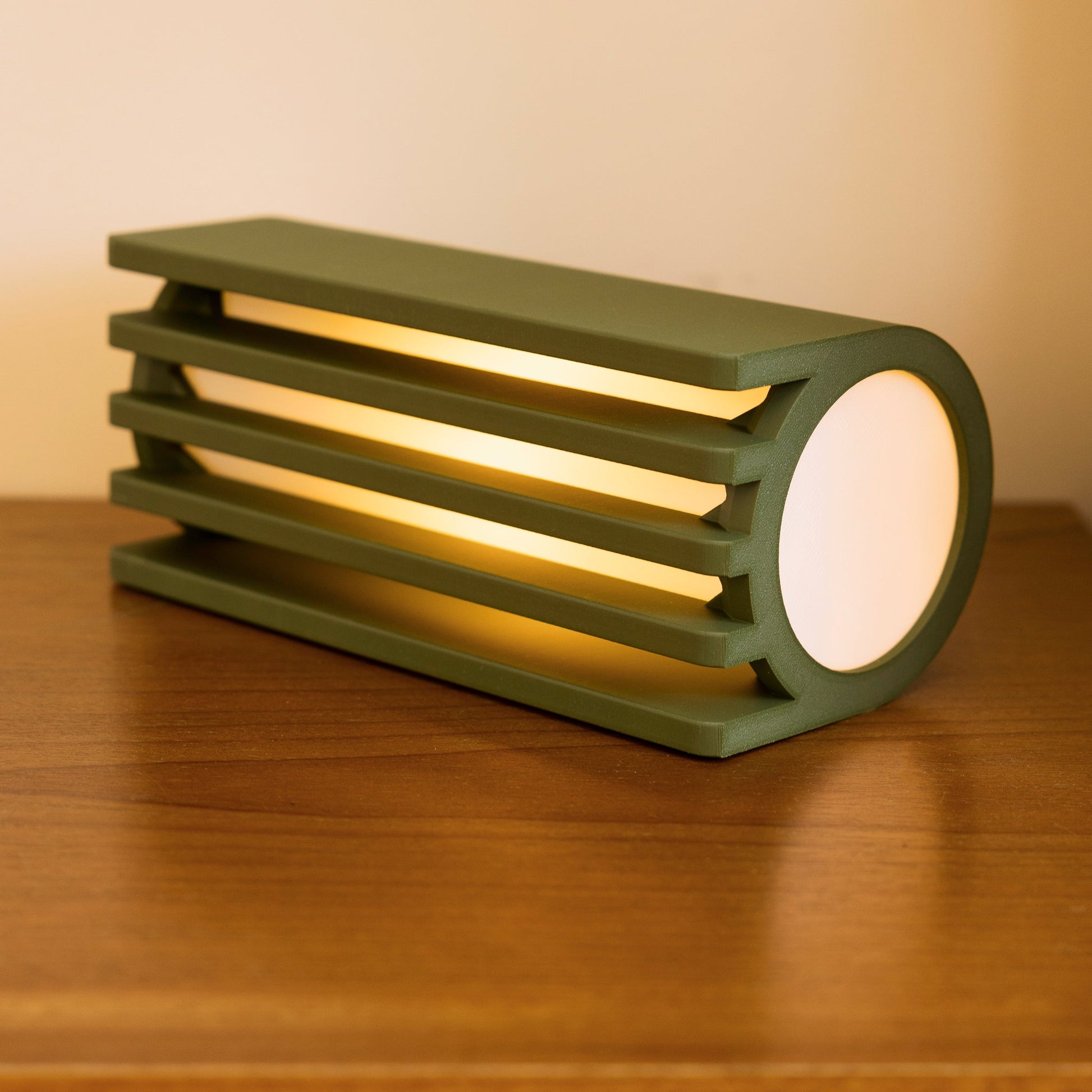 Terra Labs radiator table lamp with a sleek, olive-colored radiator-inspired design on a wooden table.