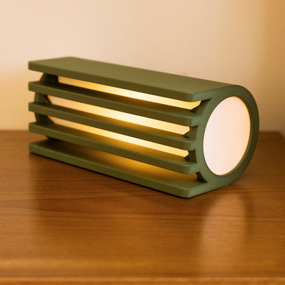 Terra Labs radiator table lamp with a sleek, olive-colored radiator-inspired design on a wooden table.