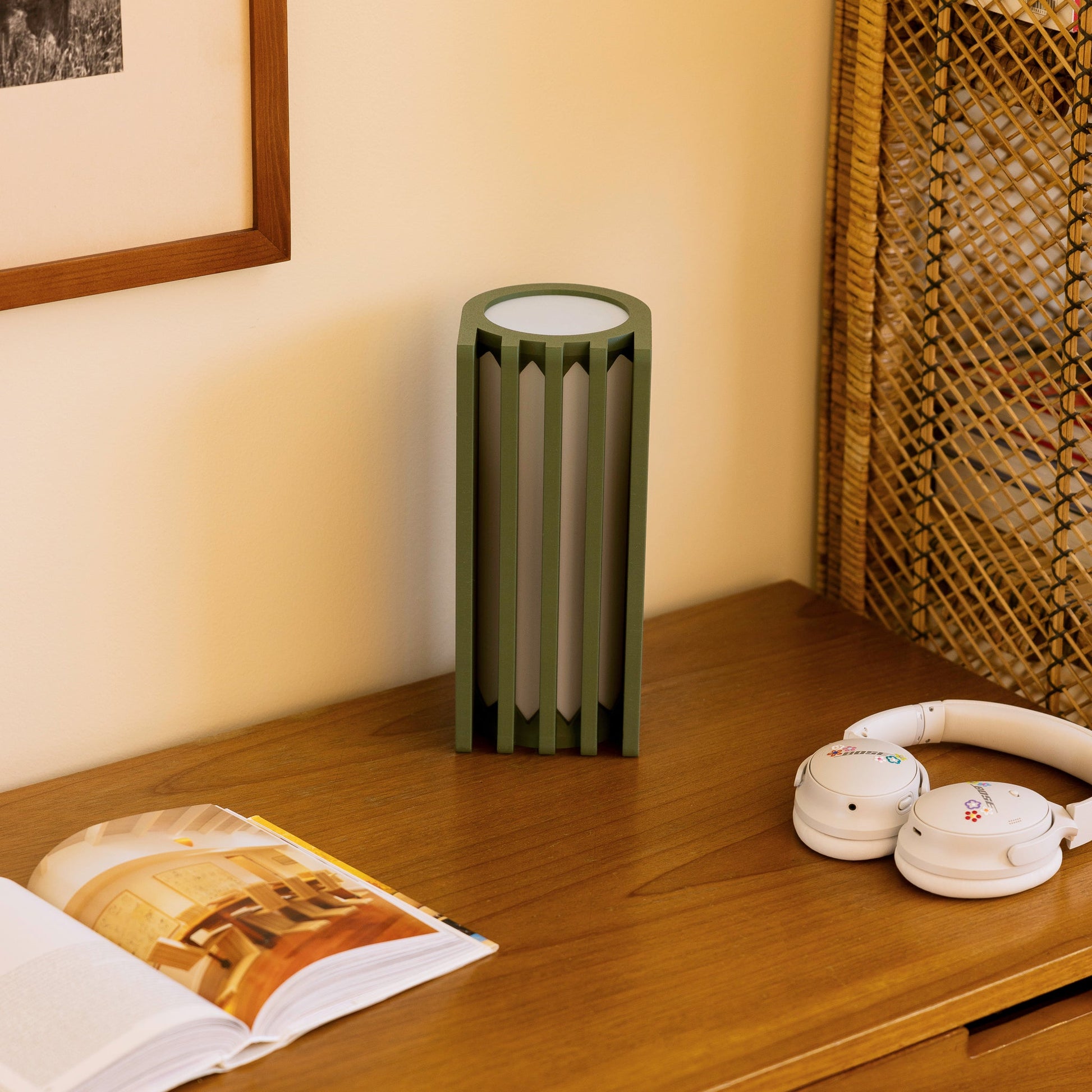 Terra Labs radiator-shaped table lamp with olive green finish, modern design, and warm illumination on a sleek surface.