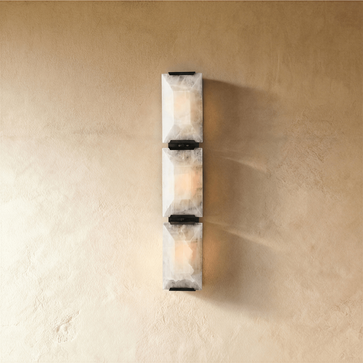 Sakhra Wall Lamp by Residence Supply featuring a modern design with a textured stone finish and warm lighting.