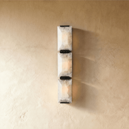 Sakhra Wall Lamp by Residence Supply featuring a modern design with a textured stone finish and warm lighting.