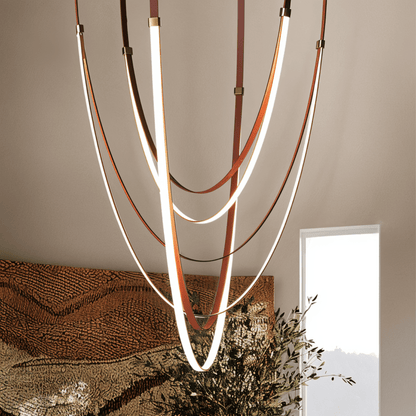 Leather chandelier with multiple hanging leather strips in warm tones, designed by Residence Supply for stylish interior lighting.