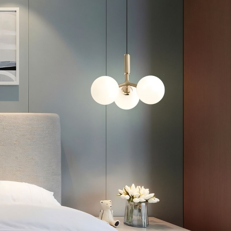 Residence Supply Trilume pendant light hanging above a bedroom nightstand, modern lighting fixture for cozy interior decor.
