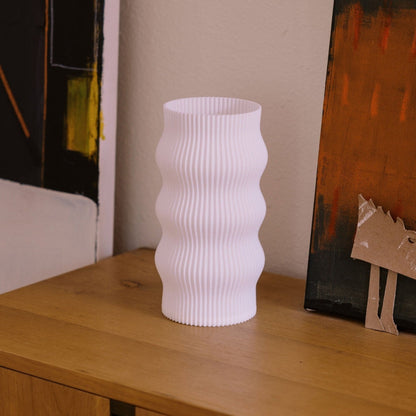 Terra Labs Wub Table Lamp with a modern design, featuring a sleek base and a soft glowing lampshade on a side table.