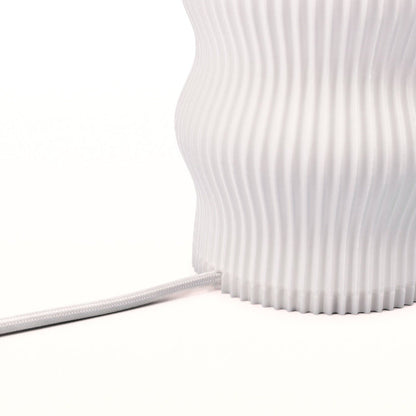 Terra Labs Wub Table Lamp with a modern, rounded design and soft glowing light on a wooden surface.