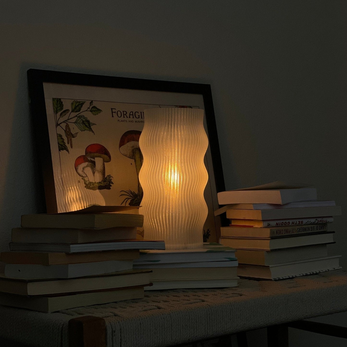 Yuji table lamp by Terra Labs featuring a modern design with a sleek base and a fabric lampshade on a wooden bedside table.