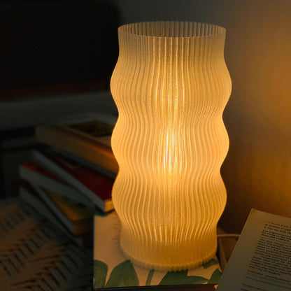 Yuji table lamp by Terra Labs with a sleek modern design and a cylindrical shade on a wooden base.