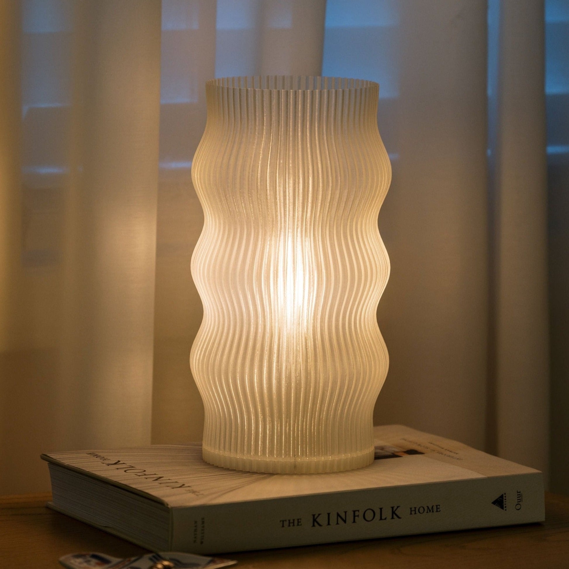 Terra Labs Yuji table lamp with a modern design, featuring a sleek base and a fabric lampshade on a wooden table.